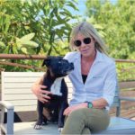 Author Louise Stapleton-Frappell sitting outside on a bench with her dog, Jambo.