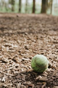 A dirty tennis ball in a park.